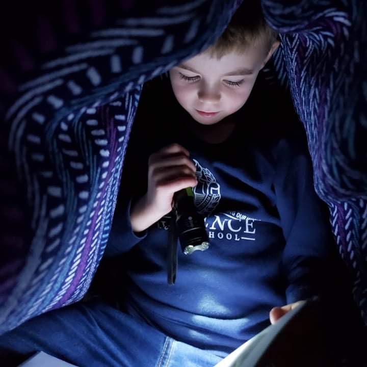 Boy reading under a blanket with a flashlight