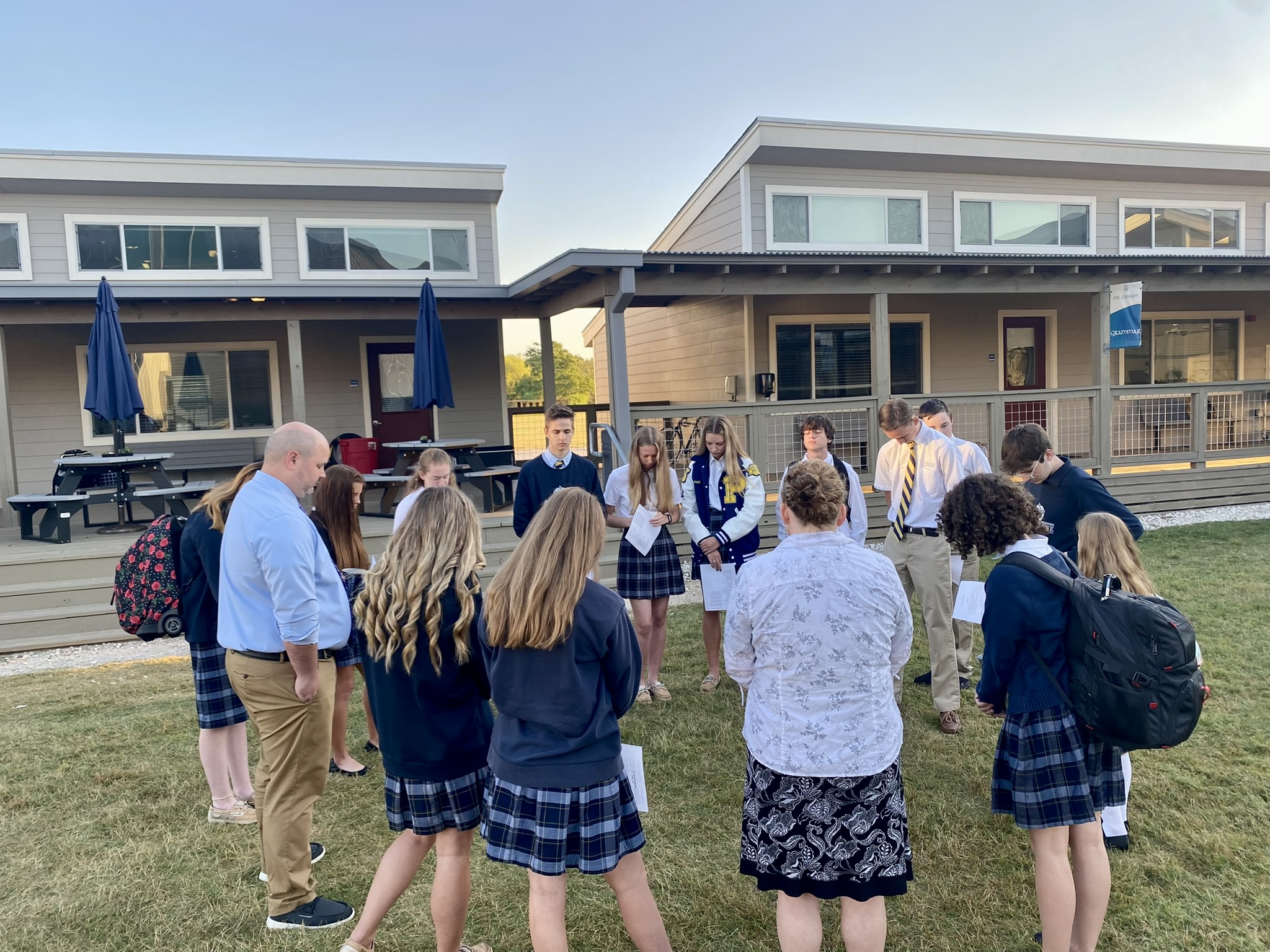 Students, teachers, and parents praying together outdoors at Providence Classical School
